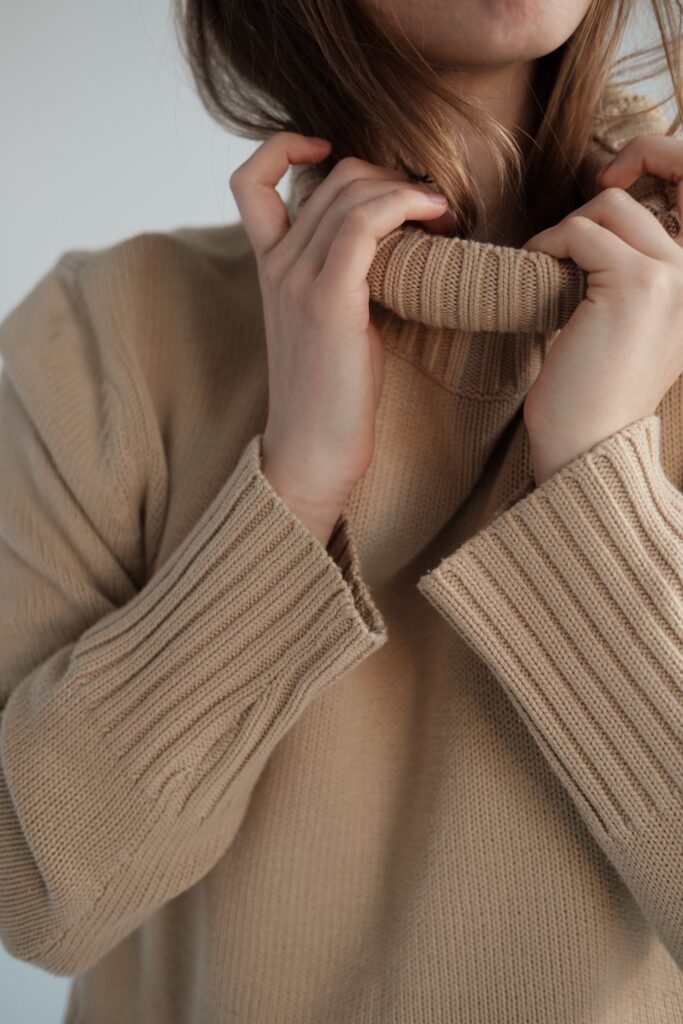 Person staying warm and cosy in a beige jumper. 