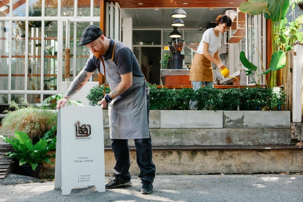 A man wearing a basic grey apron and dark t-shirt as his restaurant uniform, preparing the establishment to open. 