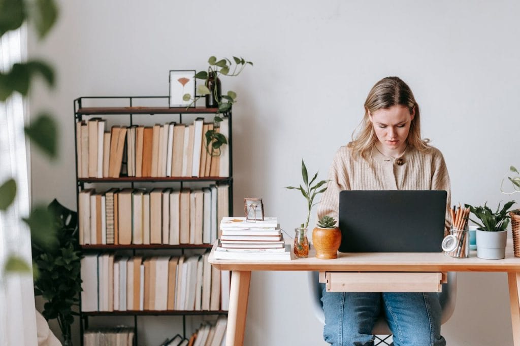 Woman working on laptop at home office desk starting t-shirt business.
